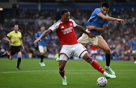 El defensa brasileño del Arsenal, Gabriel Magalhaes, pelea por el balón con el centrocampista paraguayo del Brighton, Diego Gómez, durante el partido de fútbol de la Premier League inglesa, en el American Express Community Stadium de Brighton.