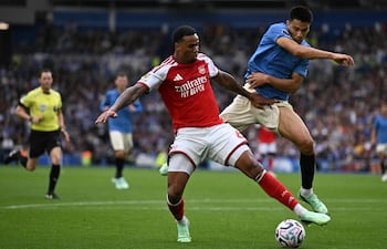 El defensa brasileño del Arsenal, Gabriel Magalhaes, pelea por el balón con el centrocampista paraguayo del Brighton, Diego Gómez, durante el partido de fútbol de la Premier League inglesa, en el American Express Community Stadium de Brighton.