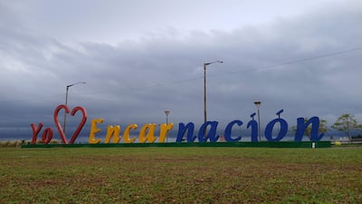 Letrero colorido 'Yo ❤️ Encarnación' sobre césped verde, sin personas, cielo parcialmente nublado.