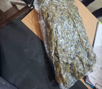 Bolsa plástica transparente con marihuana sobre mesa, rodeada de documentos en un ambiente de incautación.