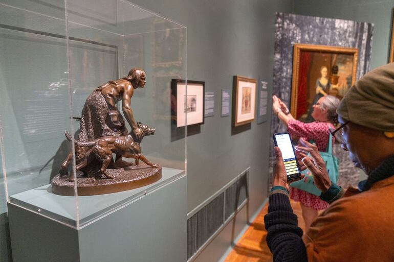 Una mujer prepara su teléfono móvil para tomar una foto a una réplica de la escultura 'The india Hunter' de John Quincy Adams Ward durante su visita a la exposición 'Pets and the City' (las mascotas y la ciudad) este viernes, en la sede del museo en Nueva York (EE.UU.).
