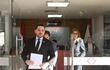 Luis Bello en traje oscuro sostiene documentos, mientras Jorge Sabaté lo acompaña, ambos frente al Ministerio Público.