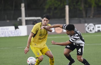 Facundo Echeguren, de Recoleta, intenta desprenderse de la marca del gumarelo Néstor Giménez. El canario venció a Libertad 2-1.