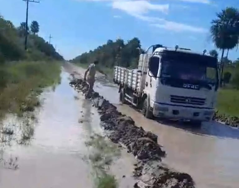 Entre el agua y el barro, el hombre busca la forma de sacar del atascadero al vehiculo.