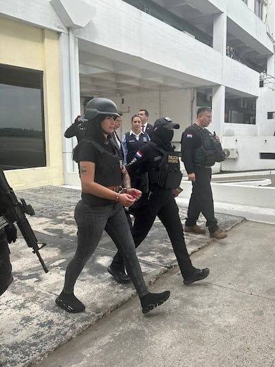 Gianina García Troche, esposada, con chaleco y casco, sale del aeropuerto Silvio Pettirossi rumbo al penal militar de Viñas Cue, tras ser extraditada desde España.