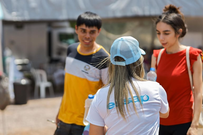 Funcionarios de la Essap entregan botellas de agua a los peregrinos en Caacupé.