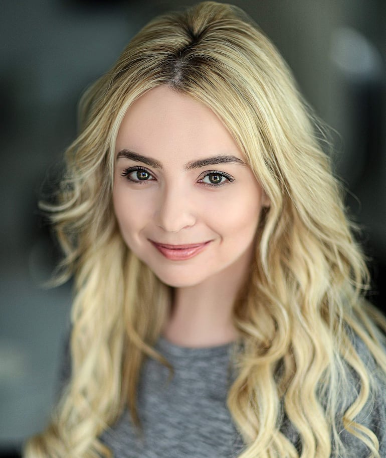 Katie Chudnovsky sonríe, luciendo su cabello rubio y en un ambiente divertido y informal.