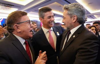 Santiago Peña en chaqueta gris sonríe mientras conversa con Mario Abdo Benítez y Pedro Alliana en un ambiente elegante.