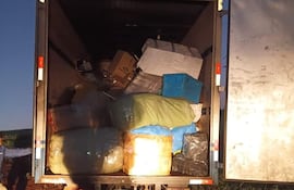 Interior de camión de carga lleno de cajas y paquetes, sin personas visibles en el entorno rural.