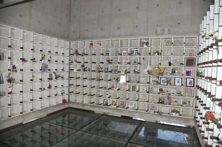 Interior del mausoleo Ycua Bolaños con urnas decoradas, flores y fotos, creando un ambiente de homenaje.