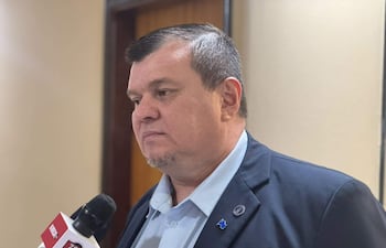 Dionisio Oswaldo Amarilla Guirland, con camisa clara y saco oscuro, mantiene una conversación seria sosteniendo un micrófono en un entorno institucional.