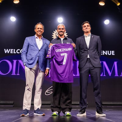 El futbolista francés Antoine Griezmann (c) posando con el dueño y presidente del Orlando City Mark Wilf (i) y el director deportivo Ricardo Moreira este martes, durante su presentación como nuevo jugador, en Orlando (FL, EE.UU.).