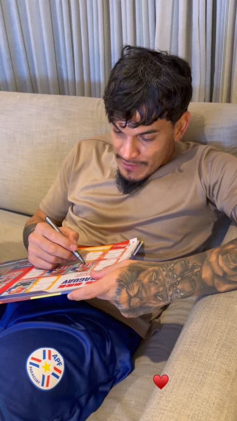 Gustavo Gómez firmando feliz el álbum de figuritas de sus hijos Lucca y Pía. (Instagram/Jazmín Torres)
