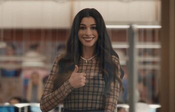Mujer con sonrisa amplia y pulgar arriba, en ambiente de oficina con detalles de trabajo al fondo.