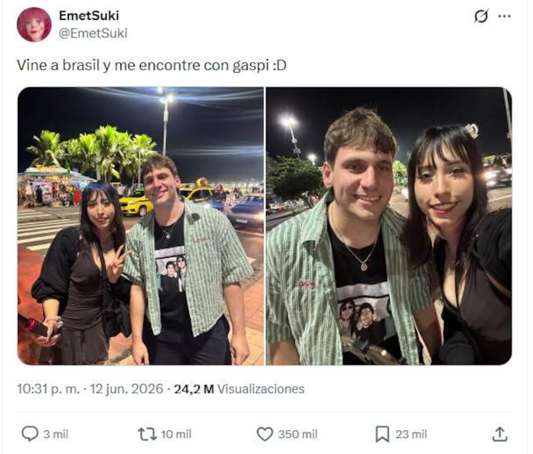Gaspi en camisa de cuadros y camiseta negra, sonriendo junto a mujer con vestido negro y señal de paz, en ambiente festivo.
