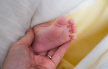 Un adulto agarra el piecito de un bebé recién nacido.