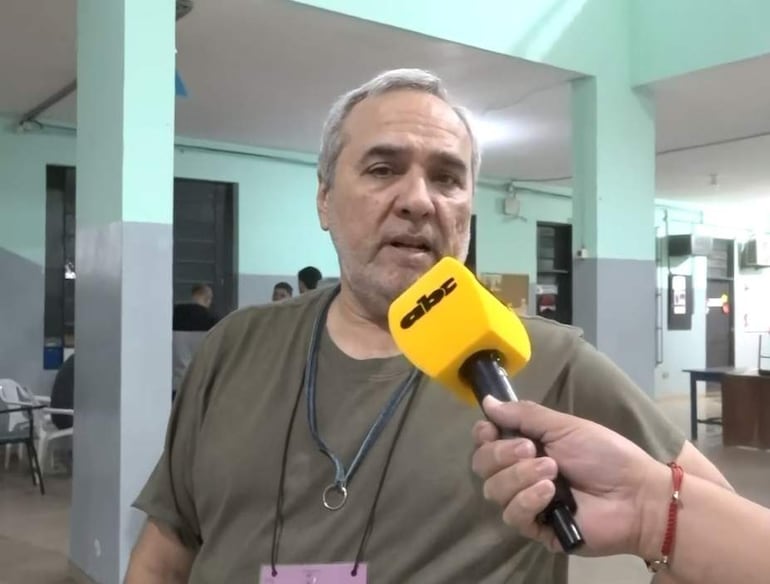 Hugo Royg, con camisa oscura y cabello canoso, frente a un micrófono de ABC mientras es entrevistado entre un grupo de personas.