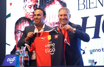 El presidente del Club Cerro Porteño, Blas Reguera (i) y el nuevo director técnico del equipo, Ariel Holan, posan con la camiseta en una conferencia de prensa este miércoles en Asunción (Paraguay).