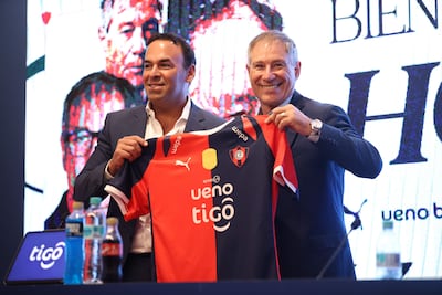El presidente del Club Cerro Porteño, Blas Reguera (i) y el nuevo director técnico del equipo, Ariel Holan, posan con la camiseta en una conferencia de prensa este miércoles en Asunción (Paraguay).