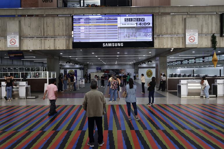 Personas observan una pantalla con la programación de los vuelos este sábado, en el Aeropuerto Internacional Simón Bolívar en Maiquetia (Venezuela).