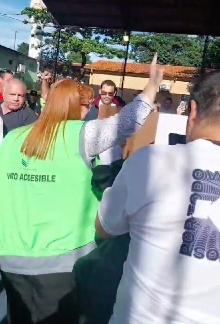 Mujer con chaleco de voto accesible del TSJE levanta el dedo índice haciendo alusión a la lista del Partido Colorado en pleno sufragio y escrache al senador colorado cartista Javier Zacarías Irún.