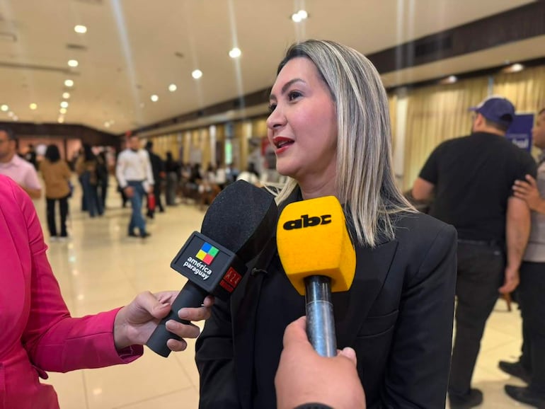 Mónica Recalde, con blazer negro, responde a periodistas en un ambiente profesional con micrófonos de 'abc' y 'América Paraguay'.