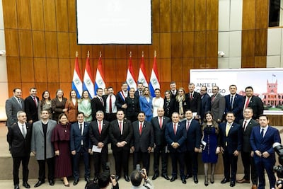 Santiago Peña en el centro, rodeado de diputados con sonrisas y banderas de Paraguay en el fondo.