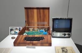 Computadora Apple-1 abierta sobre mesa blanca, junto a un televisor Sony antiguo, en un ambiente de museo tecnológico.