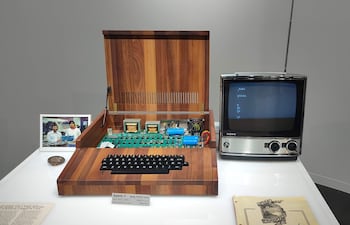 Computadora Apple-1 abierta sobre mesa blanca, junto a un televisor Sony antiguo, en un ambiente de museo tecnológico.