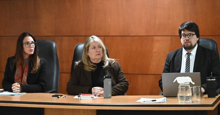 Adriana Planás y Elsa García sentadas frente a Matías Garcete, centrados en documentos y laptops en ambiente formal.