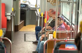 Cinco adultos sentados en un autobús eléctrico moderno, con asientos rojos y ambiente cómodo.