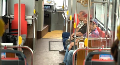 Cinco adultos sentados en un autobús eléctrico moderno, con asientos rojos y ambiente cómodo.