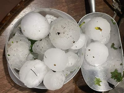 Bandeja y recipiente con bolas de granizo, manchas de tierra visibles, sobre superficie de madera.