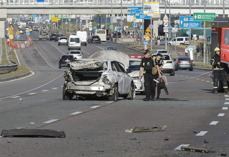 Policías ucranianos inspeccionan un coche dañado en el lugar donde cayó un dron ruso en Kiev, Ucrania, en medio de la invasión rusa. Al menos seis personas resultaron heridas, incluyendo un niño, en varios lugares de la capital ucraniana durante los ataques aéreos rusos diurnos, según el Servicio Estatal de Emergencias de Ucrania.