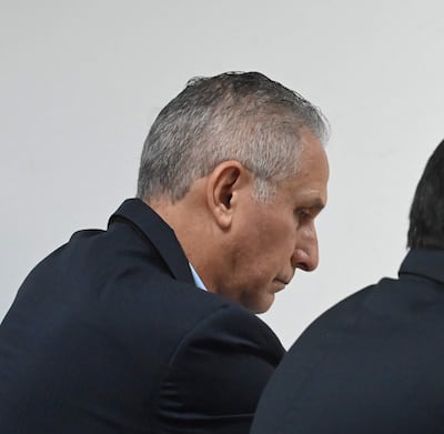 Óscar Boidanich, con chaqueta oscura y expresión tranquila, conversa con otro hombre en ambiente formal en interior.