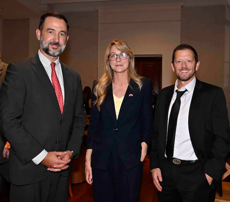 Tres personas en el evento, dos con trajes formales y corbatas, mostrando sonrisas y positividad en Hotel La Misión.