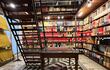 Interior de biblioteca acogedora con estanterías llenas de libros, lámpara de cristal y escalera metálica en un entorno histórico.