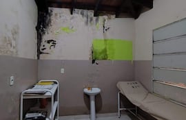 Interior de habitación deteriorada en el hospital, con paredes húmedas y una cama simple.