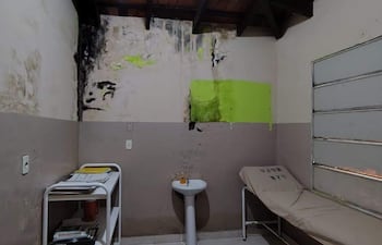 Interior de habitación deteriorada en el hospital, con paredes húmedas y una cama simple.