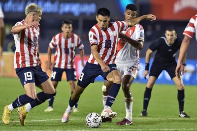 El mediocampista paraguayo Diego Gómez (C-L) y el mediocampista peruano Wilder Cartagena (atrás) luchan por el balón durante el partido de fútbol de las Eliminatorias Sudamericanas para la Copa Mundial de la FIFA 2026 entre Paraguay y Perú, en el estadio Antonio Aranda de Ciudad del Este, Paraguay, el 7 de septiembre.