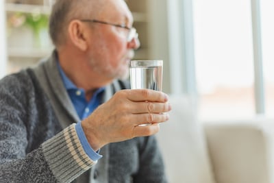 Adulto mayor bebe agua.
