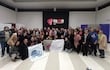 Grupo de 50 personas en la Facso-UNA, todos sonrientes y sosteniendo cartelones sobre trabajo social, en un ambiente festivo.