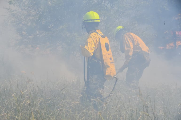 Personal militar y bomberos trabajan en medio de la humareda para sofocar incendios provocados.
