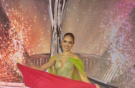 Sharon Capo en el escenario de Miss Grand International con una bandera.