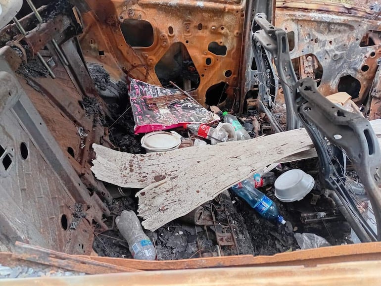 Interior de un vehículo dañado, con restos de basura y óxido, evidenciando un estado de abandono en un entorno urbano.