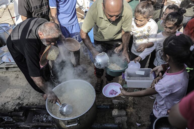 Voluntarios sirven comida a niños en un campo de refugiados de la UNRWA en Jan Yunis.
