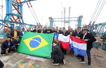 Grupo de personas con banderas de Brasil, Chile y Paraguay en el puente de la bioceànica