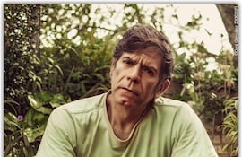 Héctor Micó con camiseta verde claro y jeans sentado en una silla moderna, rodeado de plantas con expresión reflexiva.