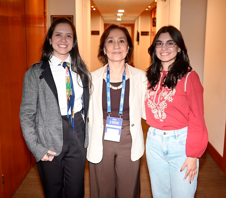 Tres mujeres sonrientes: una en camisa blanca y saco gris, otra con atuendo claro y una más en blusa roja y jeans claros.