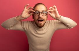 Hombre sonriente acomodándose los anteojos.